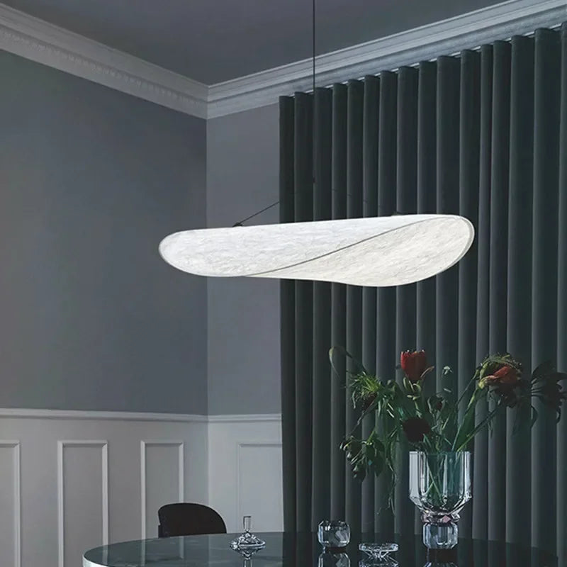 Designerski jedwabny abażur wiszący, o płynnych i eleganckich kształtach, tworzący miękkie światło dla szykownego i kojącego wnętrza.