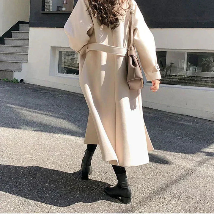 Elegancki długi płaszcz damski, dopasowana sylwetka, ciemny kolor, idealny na zimę, łączy styl i ciepło, ponadczasowy wygląd.