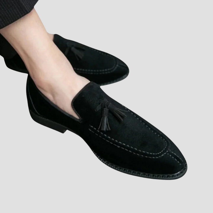 Męskie mokasyny z zamszu, widok z boku, w kolorze ciemnego brązu z eleganckimi chwostami, gumowa podeszwa, wyrafinowany styl.
