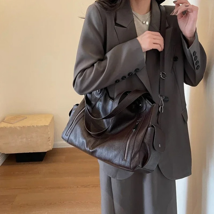 Torebka Amber na ramię w kolorze brązowym, wykonana z materiału roślinnego, z paskiem na ramię, metalowymi detalami i kieszeniami, elegancki i przestronny design dla kobiet.